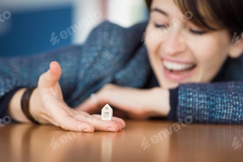 Preview: happy girl woman holds model of house in her hand and smiles. dream of owning your own real estate.