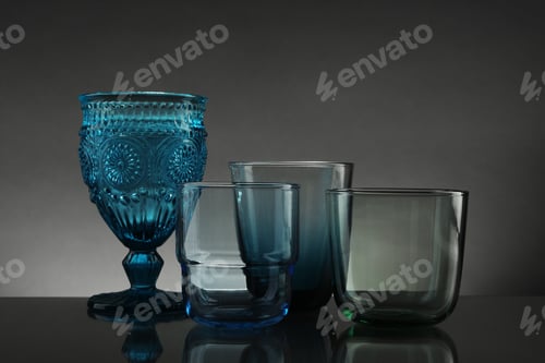 Preview: Set of different colorful empty glasses on table against grey background