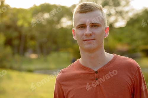 Preview: Young man with blond hair at the park outdoors
