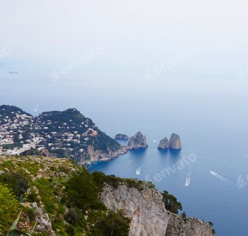Preview: View of Capri and boats sailing not far from the shore seen from the top of a mountain. Italy.