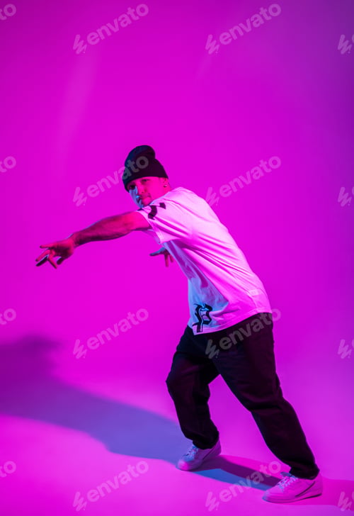 Preview: Fashion professional breakdancer man dances in creative colored studio with pink and neon light