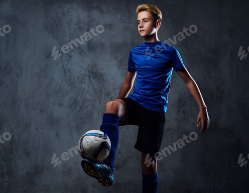 Preview: Teenager soccer player dressed in a blue uniform plays with a ball.
