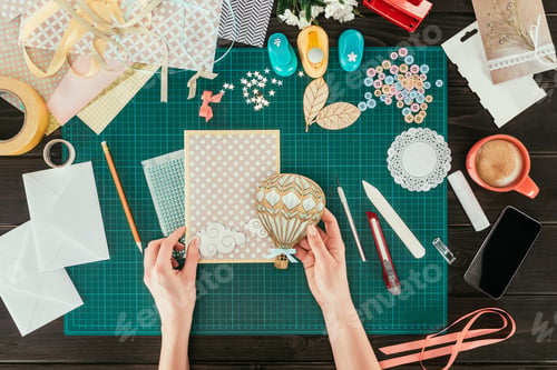 Preview: cropped image of woman adding wooden balloon to scrapbooking postcard cover
