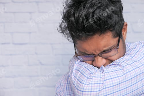 Preview: Young ill man covering her nose and mouth with arm.