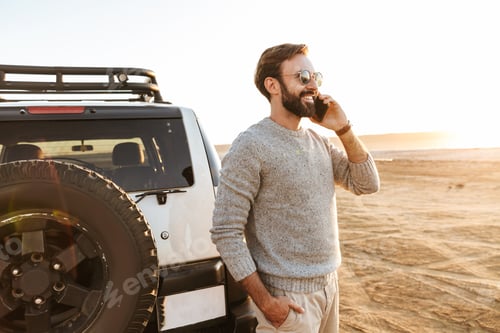Preview: Smiling handsome young man using mobile phone