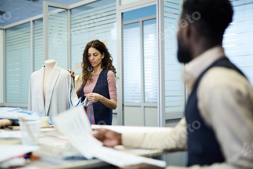 Preview: Concentrated lady saying measurements of jacket to tailor