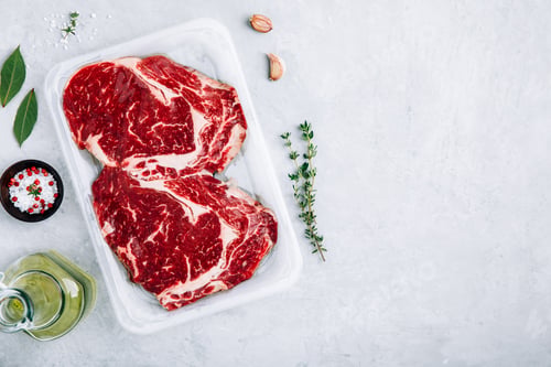Preview: Ground Beef steak in vacuum packaging with seasonings on gray stone background