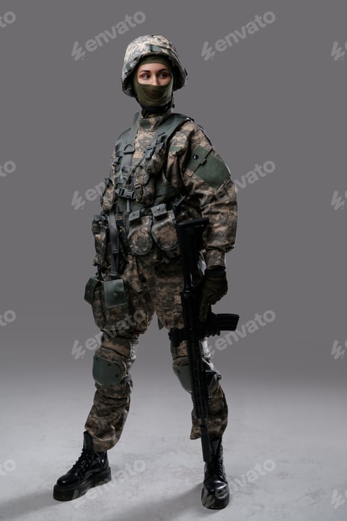 Preview: Woman soldier dressed in protective uniform against grey background