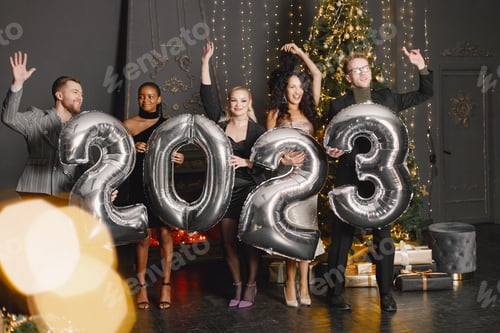 Visualização: Amigos do sexo masculino e feminino em pé com balões 2023 para a celebração do Ano Novo