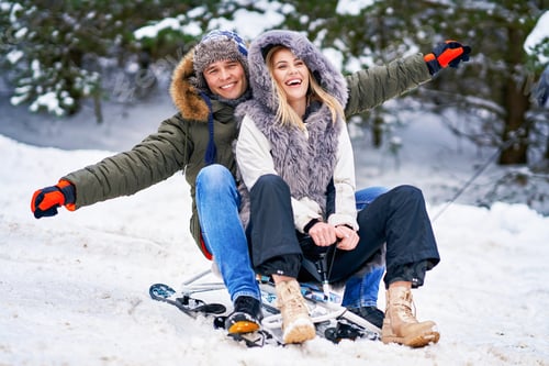 Preview: Couple having fun with sledge on snow in winter