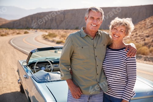 Preview: Senior couple on road trip standing by car smiling to camera