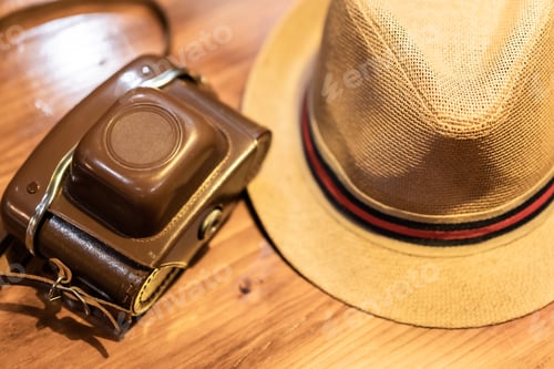 Preview: Vintage camera and a hat on a table, travel photography concept, digital nomad life