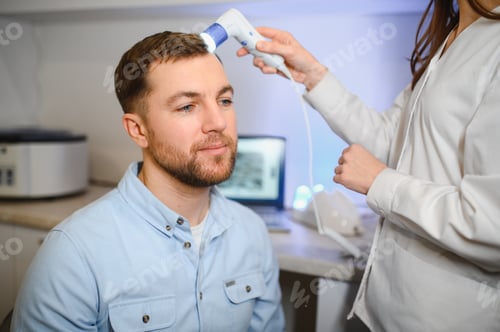 Preview: A young man is examined with a trichoscope the condition of the scalp and hair follicles