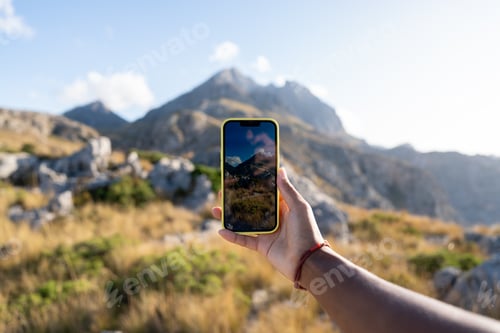 Preview: Hand holding phone taking mountain landscape picture