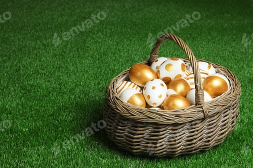 Preview: Wicker basket of traditional Easter eggs decorated with golden paint on green lawn, space for text