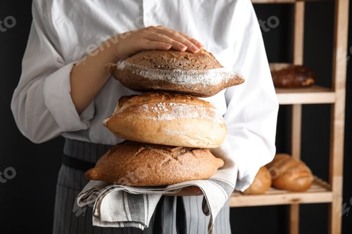 Preview: Baker holding loaves of bread indoors, closeup