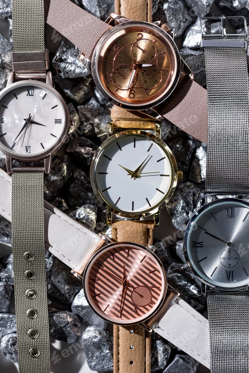 Preview: top view of elegant wristwatches lying on grey stones