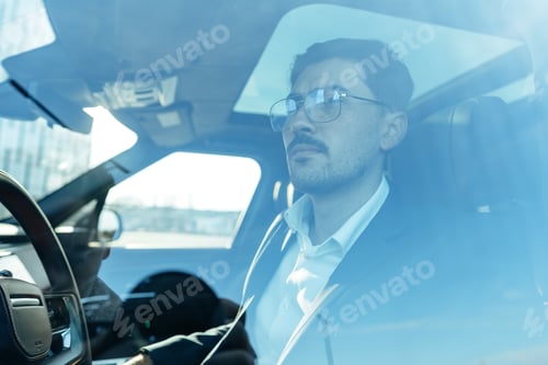 Preview: Young businessman in elegant suit driving luxury car