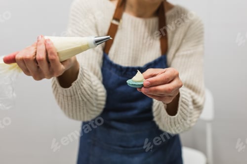 Preview: Close up view of a pastry chef filling macaroons with pastry bag while working in the pastry kitchen