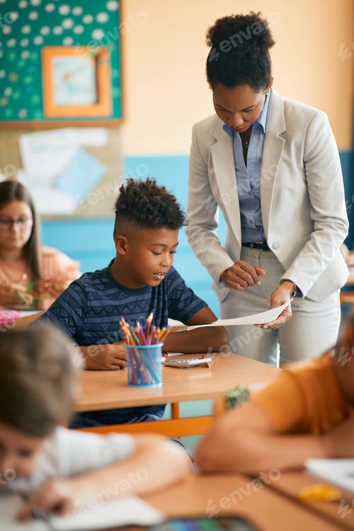 Preview: African American school teacher assisting her student during class in the classroom.