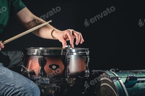 Preview: A man plays the snare drum against a dark background.