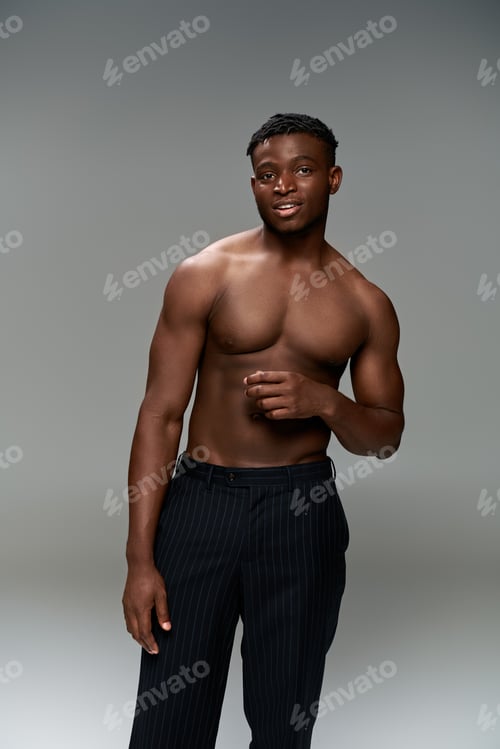 Preview: positive african american fitness model with shirtless torso looking at camera on grey backdrop