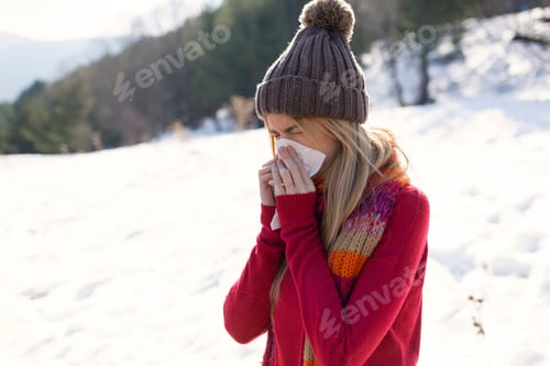 Preview: Young blond woman blowing nose in winter