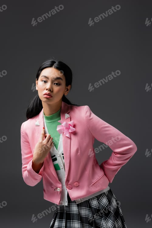 Preview: Stylish asian woman in pink jacket posing isolated on grey