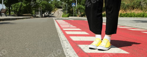 Preview: Stylish yellow sneakers on women's legs on the asphalt