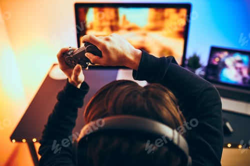 Preview: Man playing video game at home. Gamer holding gamepads sitting at front of screen. Streamer playing