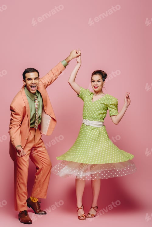 Preview: cheerful dancers holding hands while dancing boogie-woogie on pink background