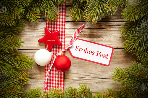 Preview: Christmas ornaments and tree branches with a "Frohes Fest - Happy Holiday" written on a tag