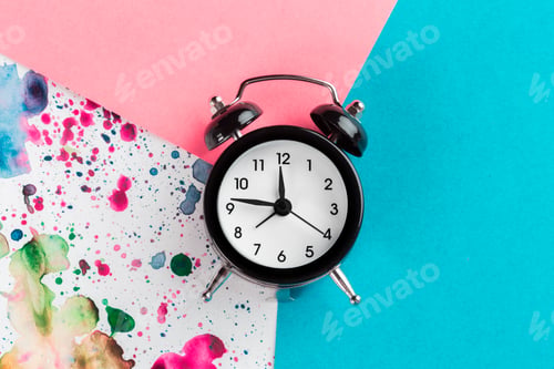 Preview: Vintage alarm clock on a creative colorful background with paint sprinkles
