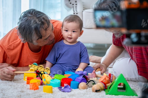 Preview: A man and a woman are playing with a baby and a bunch of toys. The baby is looking at the camera and