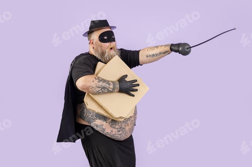 Preview: Bellicose fat man in Zorro costume with boxes of pizza stands on purple background