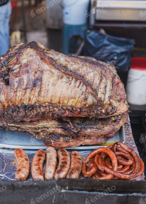 Preview: Person grilling meat on a rustic grill in Mexico. Street stall of grilled meat.