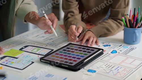 Preview: User Interface Design. Team discussing digital mockups and color palettes on a tablet.