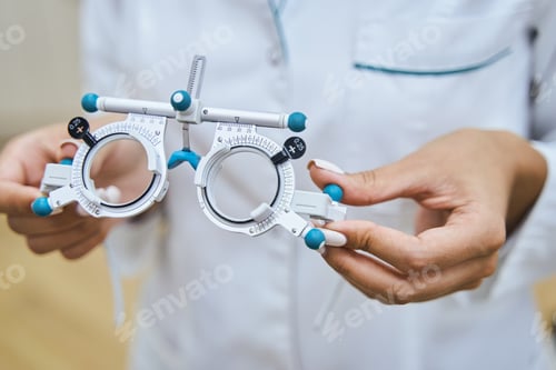 Preview: Female doctor hands holding optical trial lens frame