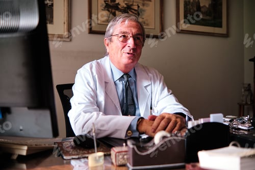 Preview: old doctor at his desk consulting
