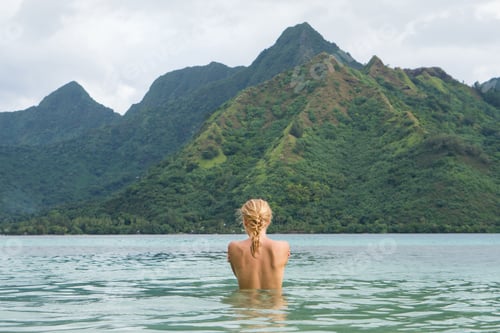 Preview: View from behind woman in the water looking at the mountains
