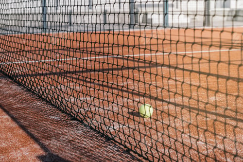 Preview: ball in net in a padel court with orange grass