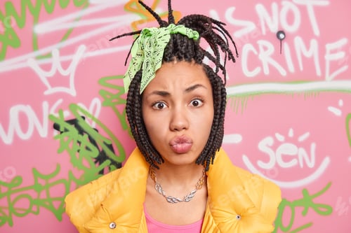 Vista previa: Photo of fashionable teenage girl make grimace at camera pouts lips has combed dreadlocks belongs to