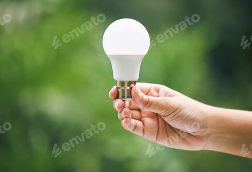 Preview: Closeup of a hand holding a light bulb in nature. New ideas for sustainable energy option. Green en