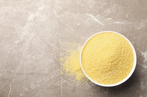 Preview: Bowl with raw couscous on gray background