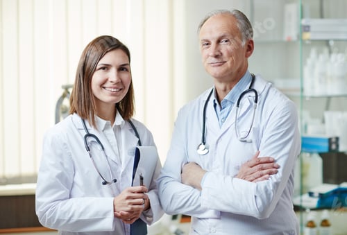 Two Doctors in White Coats Smiling in Office