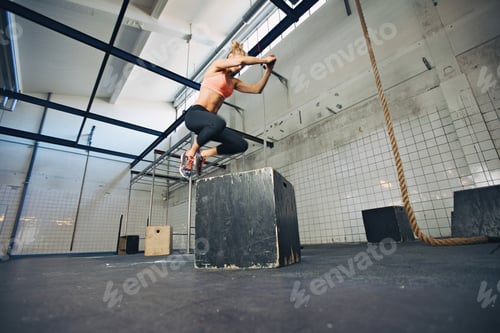 Preview: Fit woman is performing box jumps at gym