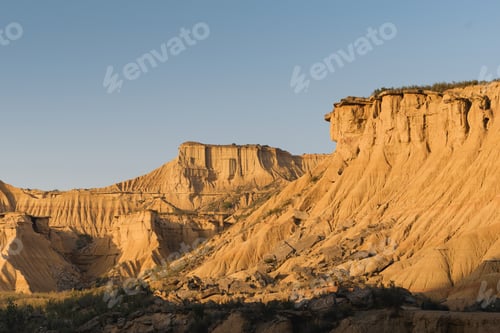 Preview: Golden hour sunlight highlighting unique eroded sandstone formations in the bardenas reales desert