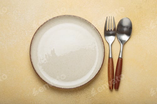 Preview: Empty plate with fork and spoon on yellow textured background top view