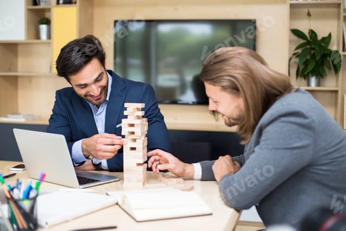 Preview: Team of young business people build a wooden construction in the office