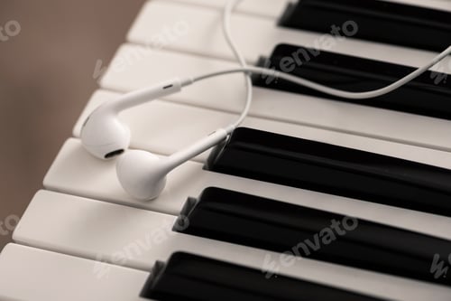 Preview: Closeup of earphones over piano or synthesizer keyboard